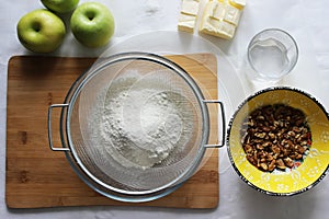Preparations for Apple pie: flour, apples, butter, nuts. Homemade cake