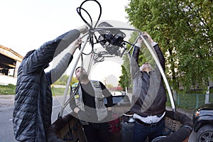 Preparations for ballooning: men standing in a basket and checking anchorages of a gas burners