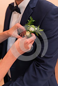 Preparations for the wedding the groom. Bride puts on boutonniere on groom`s jacket.