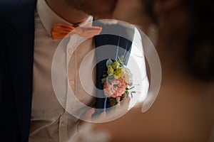 Preparations for the wedding the groom. Bride puts on boutonniere on groom`s jacket. Romantic wedding moment