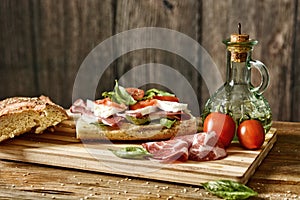 Prepare a sandwich with Italian ham, mozzarella and tomato - eat healthy and traditional - desaturated effect - selective focus