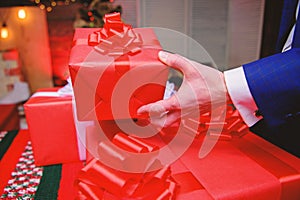 Prepare surprise gifts for family and friends. Gift boxes with big ribbon bow close up. Red wrapped gifts or presents