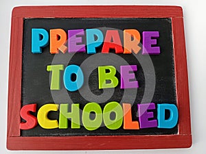 Prepare to be schooled written on a chalkboard photo