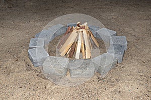 Prepared chopped pieces of wood to make a fire in a stone circle on the sand.