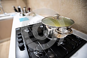 Prepared delicious dinner food pasta or soup or stew in big steel pan, cool down under lid, stand on gas-stove cooker