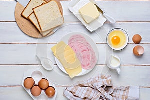 Prepared ingredients for making a hot croque madame sandwich on a white wooden background. Recipes for sandwiches, hot breakfasts