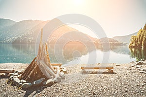 Prepared for kindling a large bonfire and benches from the logs on the shore of a beautiful lake with clear water surrounded by mo