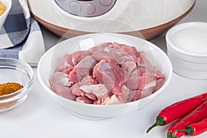Prepared meat and other ingredients ingredients for cooking pilaf in modern multi cooker in kitchen on a table. Cooking pilau with