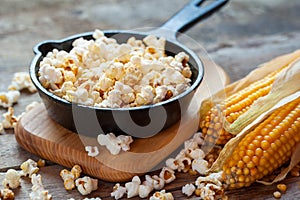 Prepared popcorn in frying pan, corn seeds and corncobs