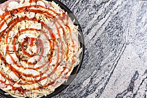 Prepared raw pizza with mushrooms cheese ham and ketchup on the grey granite table with copy space