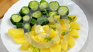 Prepared served dish with boiled potatoes, butter, pickles decorated fresh dill.