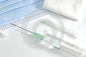 Prepared syringe with needle, sterile gauze, and surgical mask.