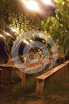 Prepared table for a rustic outdoor dinner at night with lamps