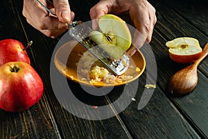 Preparing apple dessert using a grater in the hands of a chef on the kitchen table. Low key concept of healthy vitamin food