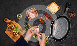 Preparing bacon wrapped asparagus on dark table.  Woman cooking asparagus. Ingredients for cooking on black background