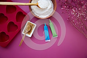 Preparing for baking: heart-shaped silicone mold, cane sugar, glaze, flour, sugar on pink background. Copy space