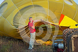 Preparing the baloon. hot air. big baloon. flight. come fly with me. in the field. yellow baloon. summer fun. a men holding baloo