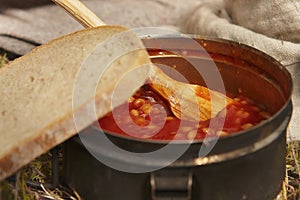 Preparing beans, bread and bacon for food in wild nature