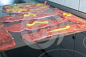 Preparing beef rouladen, fresh raw meat coated with mustard and onions