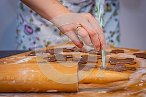 Preparing for Christmas, hand holding a straw makes holes in gingerbreads ready for baking