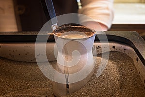 Preparing coffee in coffee jezva in sand. Turkish method of preparing coffee.