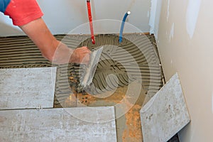 Preparing a concrete floor for tiling by troweling adhesive onto surface