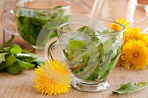 Preparing dandelion tea by pouring hot water over fresh dandelion leaves