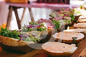 Preparing delicious burgers. Fresh burger buns with vegetables and sauce on the wooden table, selective focus