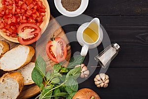 Preparing delicious Italian tomato bruschetta with chopped vegetables, herbs and oil