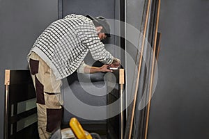 Preparing the door for installation. A man installs a door handle