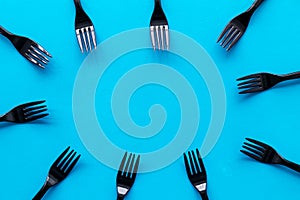 Preparing food concept for restaurant menu with plastic forks frame on blue background top view