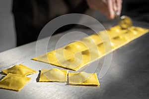 Preparing fresh made ravioli with ricotta cheese inside pasta factory.