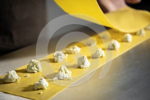 Preparing fresh made ravioli with ricotta cheese inside pasta factory.