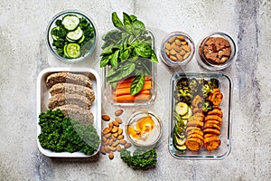 Preparing healthy food for the week, top view. Vegan food and healthy snacks in containers, gray background