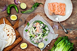 Preparing healthy lunch snacks. Fish tacos with grilled salmon, red onion, fresh salad leaves and avocado cilantro sauce