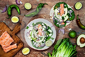 Preparing healthy lunch snacks. Fish tacos with grilled salmon, red onion, fresh salad leaves and avocado cilantro sauce