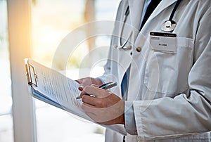 Preparing his prognosis. Closeup shot of a doctor holding a clipboard reading a medical chart.