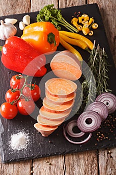 Preparing ingredients: raw sweet potatoes, peppers, tomatoes, on