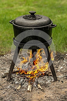 Preparing a meal outdoors in a black cast-iron pot.