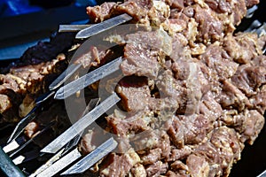 Preparing meat for grilling. Grilled kebab cooking on metal skewer. BBQ fresh pork meat chop slices. Eastern dish, shish kebab.