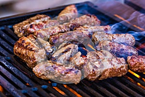 Preparing meat rolls called mici or mititei on barbecue. close up of grill with burning fire with flame and smoke