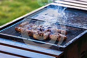 Preparing meat rolls called mici or mititei on barbecue. close up of grill with burning fire with flame and smoke