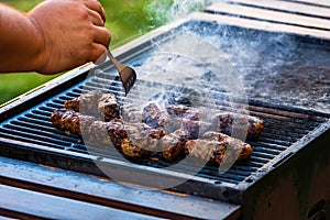 Preparing meat rolls called mici or mititei on barbecue. close up of grill with burning fire with flame and smoke