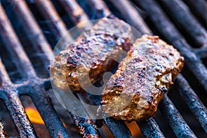 Preparing meat rolls called mici or mititei on barbecue. close up of grill with burning fire with flame and smoke