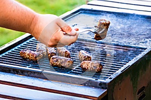 Preparing meat rolls called mici or mititei on barbecue. close up of grill with burning fire with flame and smoke