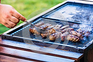 Preparing meat rolls called mici or mititei on barbecue. close up of grill with burning fire with flame and smoke