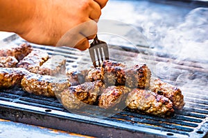 Preparing meat rolls called mici or mititei on barbecue. close up of grill with burning fire with flame and smoke