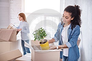 Cheerful young girls unpacking plant and blanket