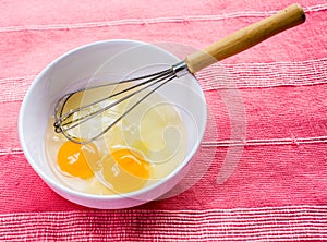 Preparing omelet with eggs and whisk