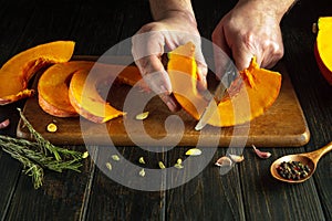 Preparing ripe pumpkin. The cook uses a knife to cut the pumpkin before preparing the pie